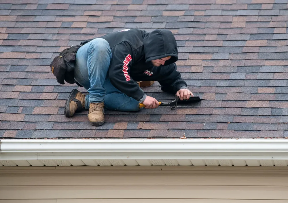 Professional roofer examining shingles and flashing during a detailed roof inspection