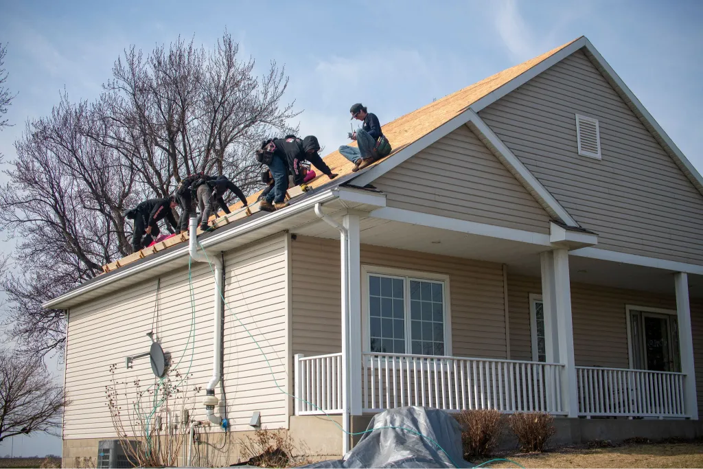 Roofers in the process of replacing old shingles with new materials during a roof replacement project