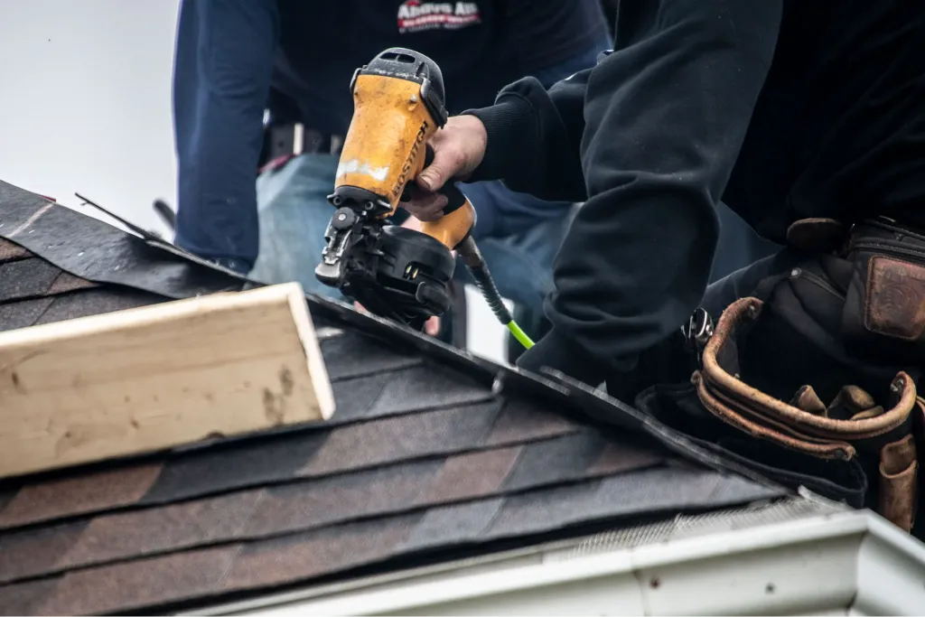 Roofer repairing damaged shingles on residential roof to restore protection and prevent leaks