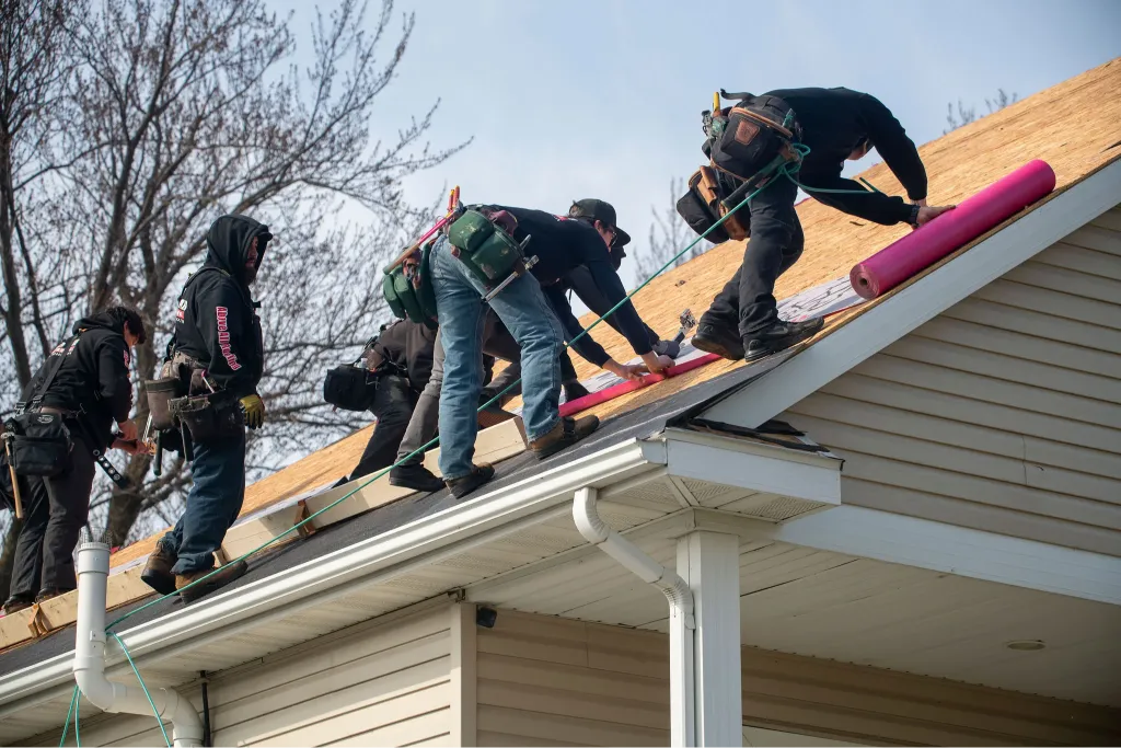 Roofer wearing safety gear while performing maintenance work on a residential roof