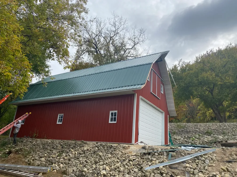 Above All Roofing team installing a new, weather-resistant roof on a large red barn in Rochester