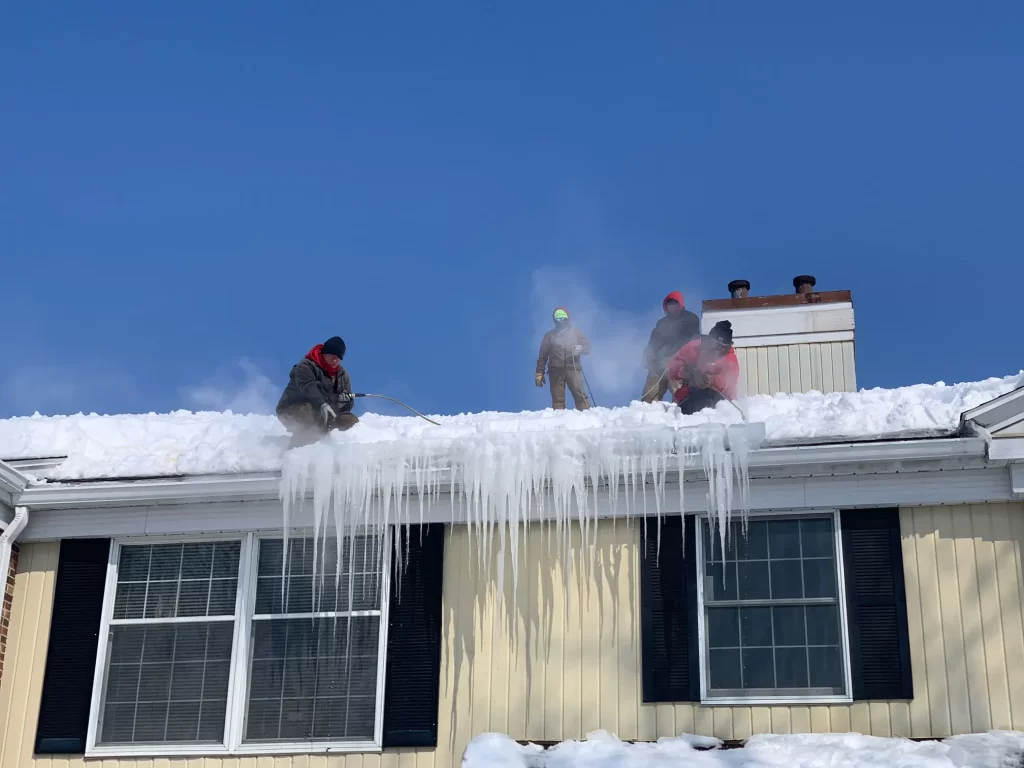 Close-up of snow being cleared off a roof to avoid water damage and ice dams during Minnesota winter