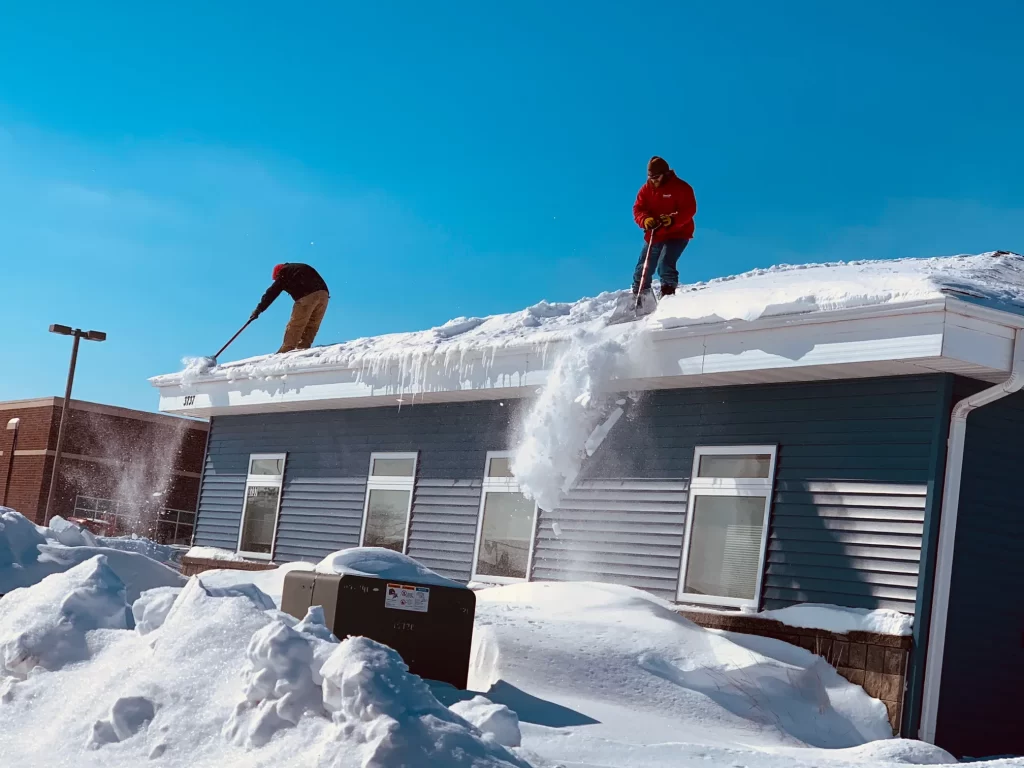 Roofing expert from Above All Roofing safely removing heavy snow from a pitched roof after a storm