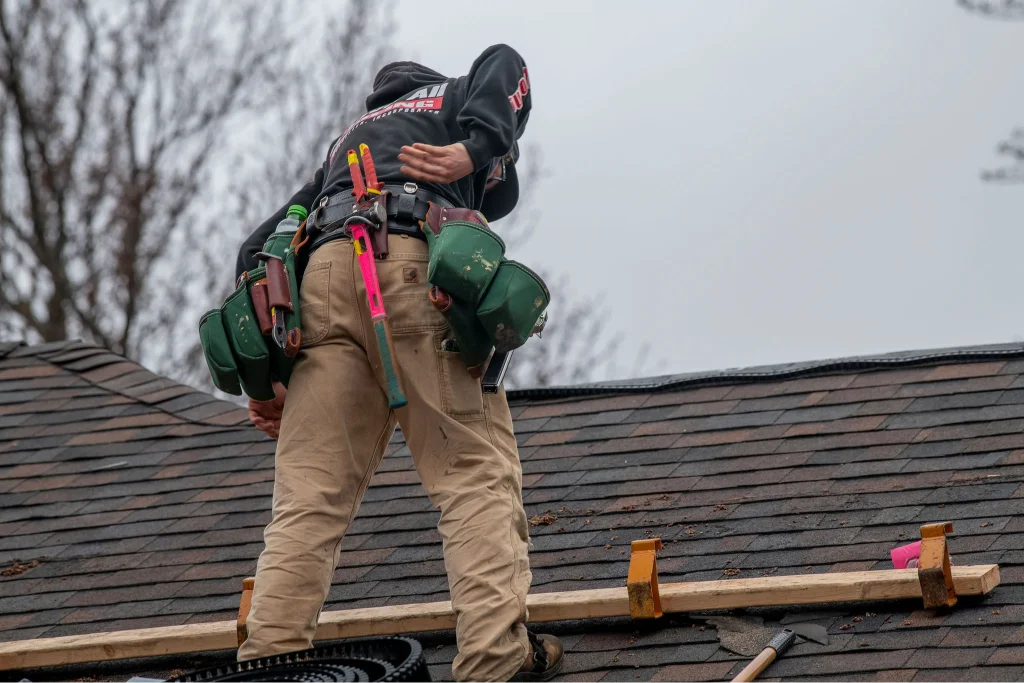 Roofer climbing a ladder to inspect roof edges during a spring maintenance visit