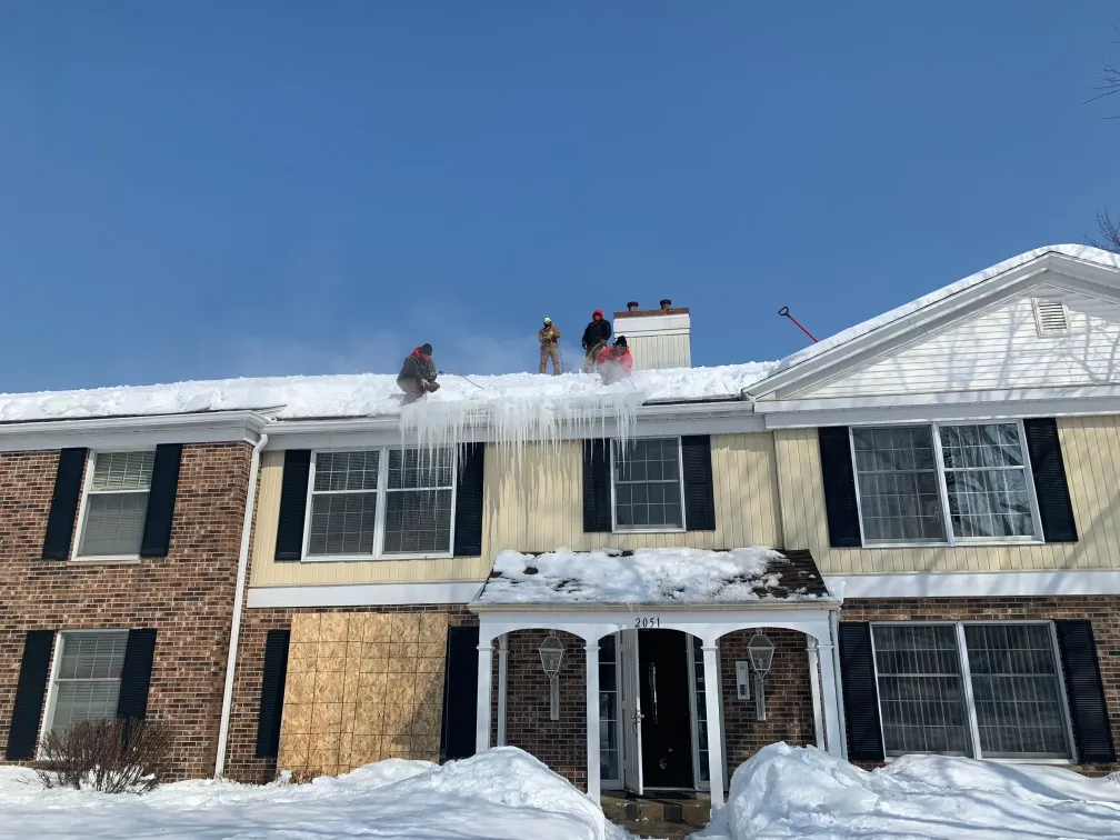 Above All Roofing crew using safety gear while performing rooftop snow removal in subzero conditions