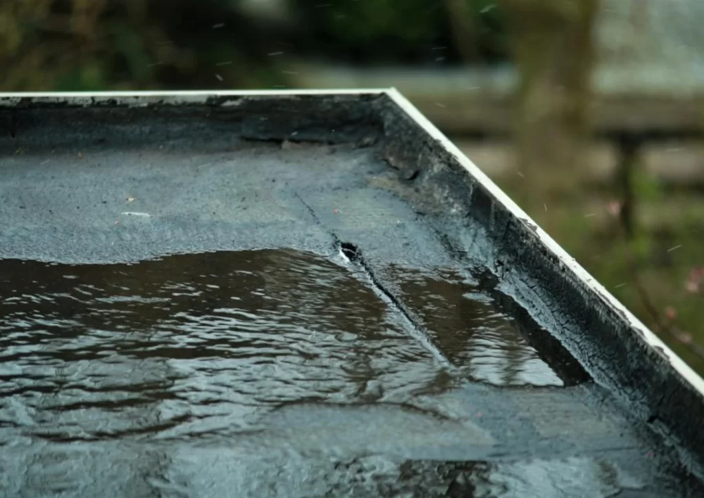 Flat roof holding water due to a leak, demonstrating flat roof repair methods by Above All Roofing